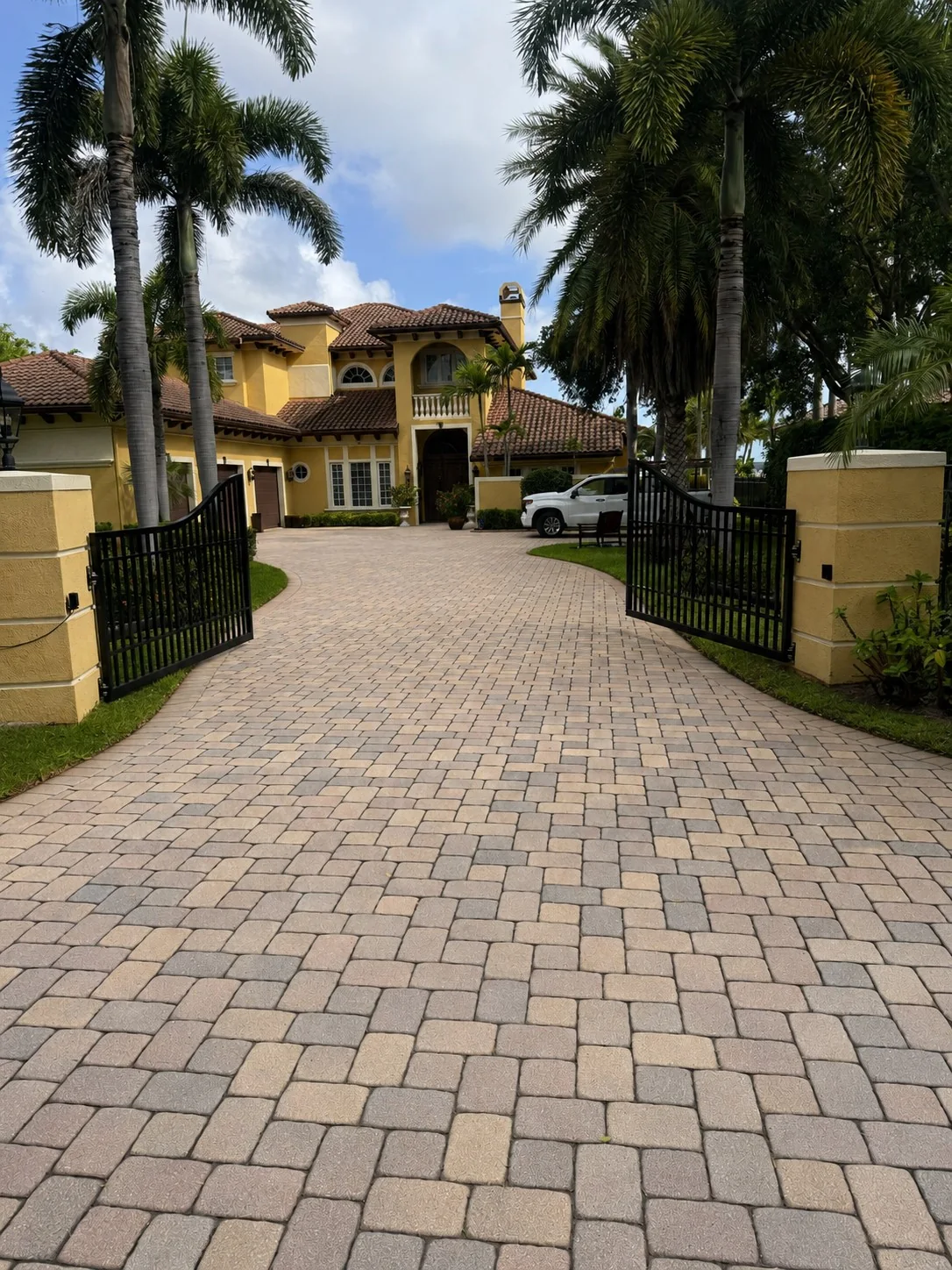Pressure washing at an upscale St. Lucie River home in downtown Stuart, Florida, with a palm-lined paver driveway